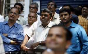 People look at a large screen displaying India's benchmark share index on the facade of the Bombay Stock Exchange building in Mumbai